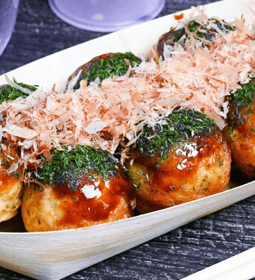 Crispy deep fried takoyaki served in a boat with sauce and bonito flakes in Singapore